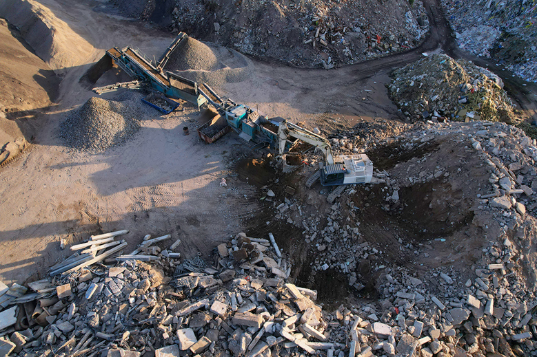 Maskiner arbejder i grusgrav med sortering af brugt byggemateriale.